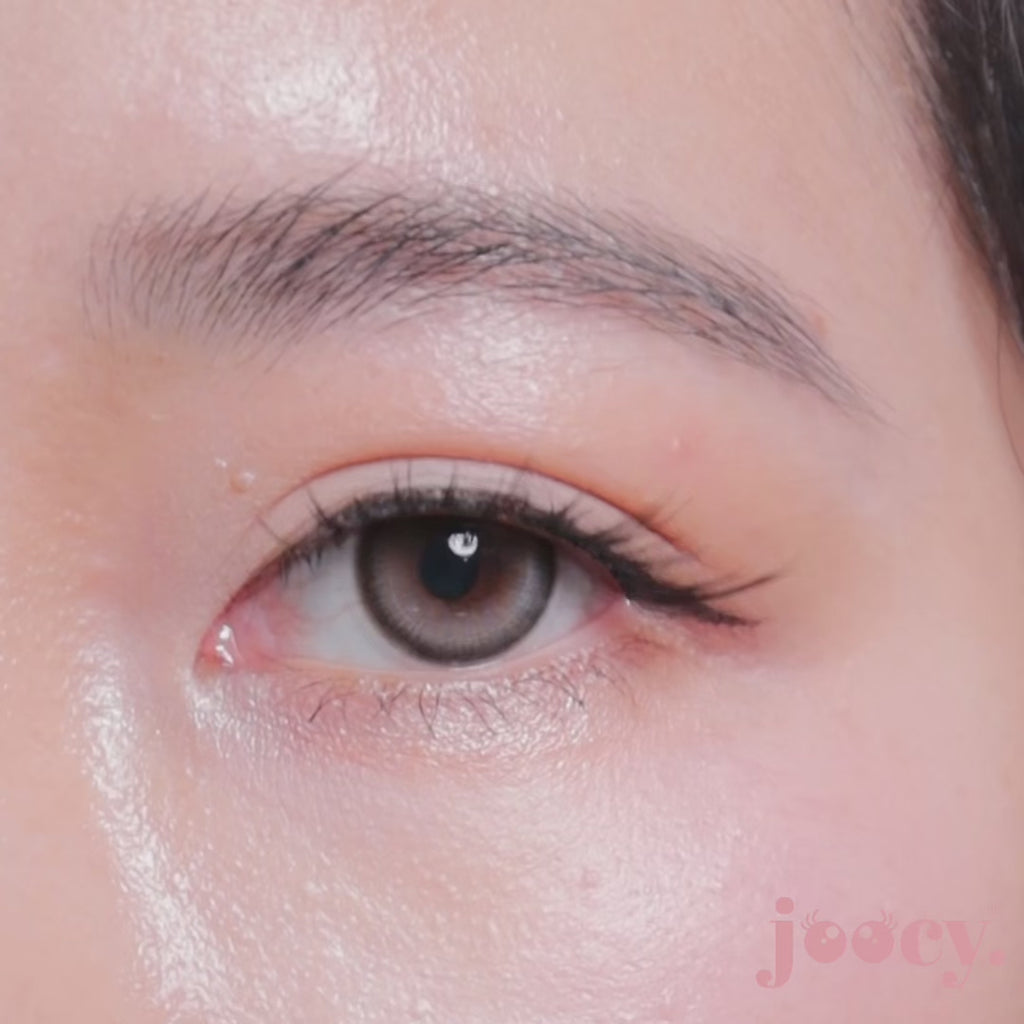 A macro close-up video of a single eye blinking on a fair-skinned model to show the joocy grey-brown lens in shade IT Girl. The iced-grey doll-eye highlight creates a dimensional gaze that pops with luminous intensity on deep skin tones too.