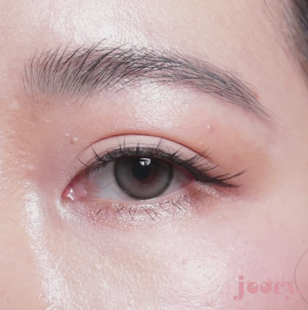 A macro close-up video of a single eye blinking on a fair-skinned model to show the joocy natural ash-grey lens in shade QT Pie. The ethereal idol-glow gradient creates a soft, smoky-quartz dimension on deep skin tones too.