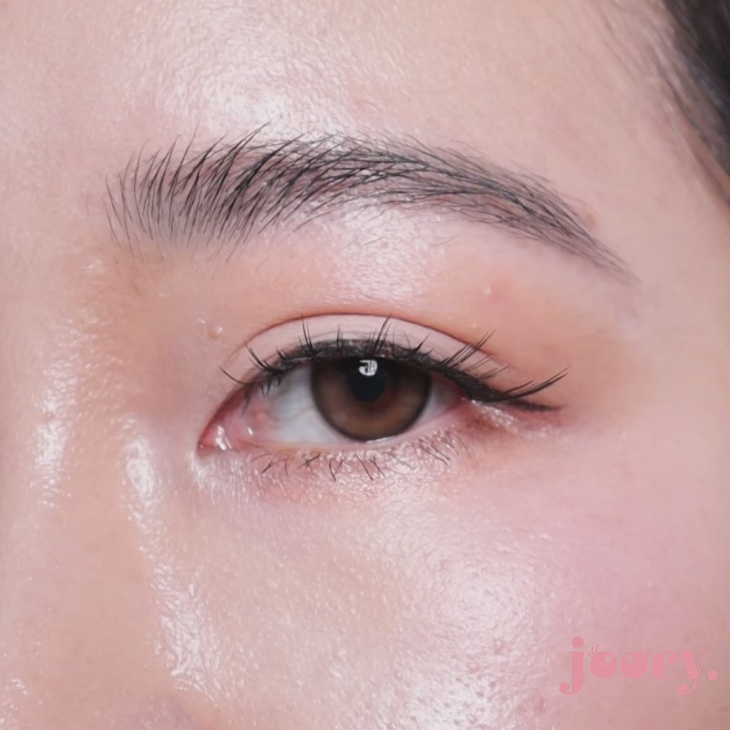 A macro close-up video of a single eye blinking on a fair-skinned model to show the joocy natural brown cosmetic lens in shade Delicious. The motion showcases the hyper-realistic sepia brown pattern, designed to flatter both fair and deep skin tones.