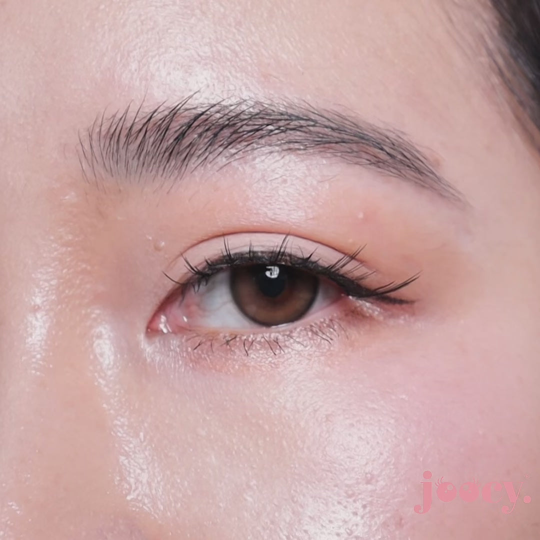 A macro close-up video of a single eye blinking on a fair-skinned model to show the joocy natural brown cosmetic lens in shade Delicious. The motion showcases the hyper-realistic sepia brown pattern, designed to flatter both fair and deep skin tones.